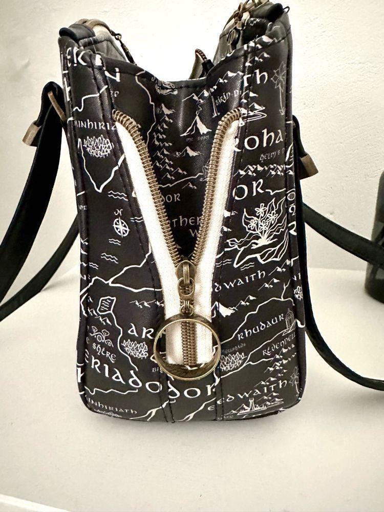 The side of the bag. It has a zipper so that the bag can expand. The zipper pull is a large bronze ring with Elvish script, resembling The One Ring. 