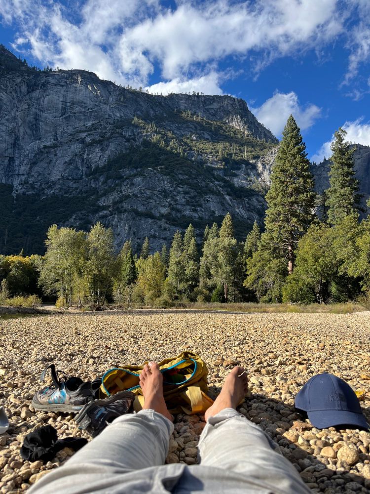 my feet on a pebble beach on the merced river on the valley floor. Looking up at the valley walls, somewhere near yosemite falls. 