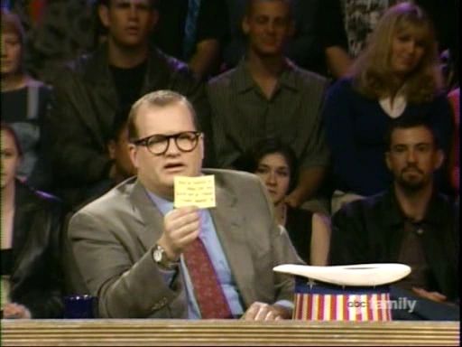 Drew Carey from "Who's Line Is It Anyway" looking at a card drawn from a 4th of July themed hat.