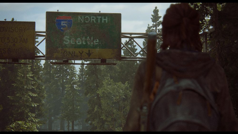 Ellie, from the video game, the last of us, overlooks a highway sign that says seattle, indicating she has made it the city to begin her quest for vengeance.
