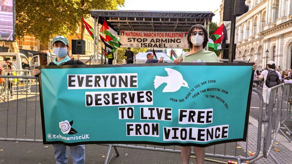 Lauren and Dane hold up a teal banner that says "Everyone deserves to live free from violence"