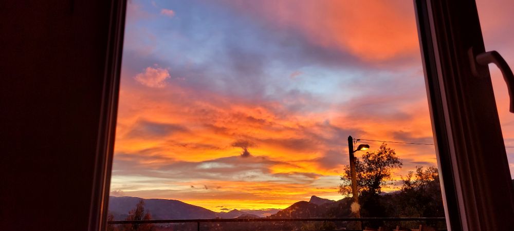 Soleil couchant 
Ciel orange et bleu  avec au fond les montagnes 
