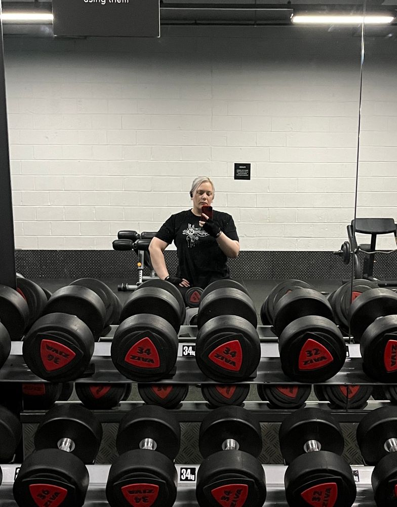 A gym mirror selfie. I’m sitting on a bench in front of a heavily laden weight rack. 