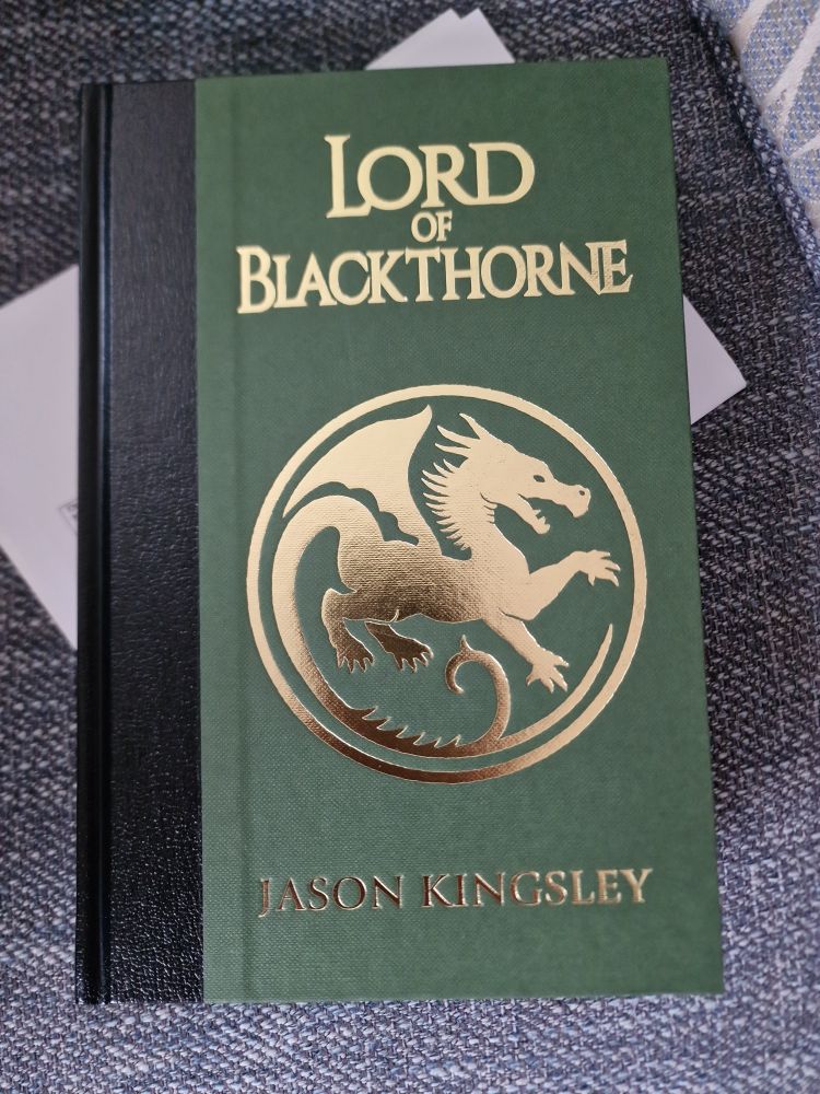 Special edition novel Lord of Blackthorne by Jason Kingsley, it's a green cover with gold lettering, the centre of the cover features a golden dragon in a circle.