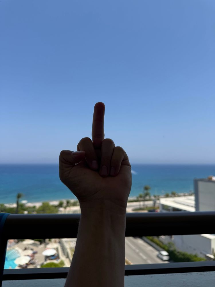 Sitting on a balcony with my left hand making a "fuck you" gesture towards the ocean