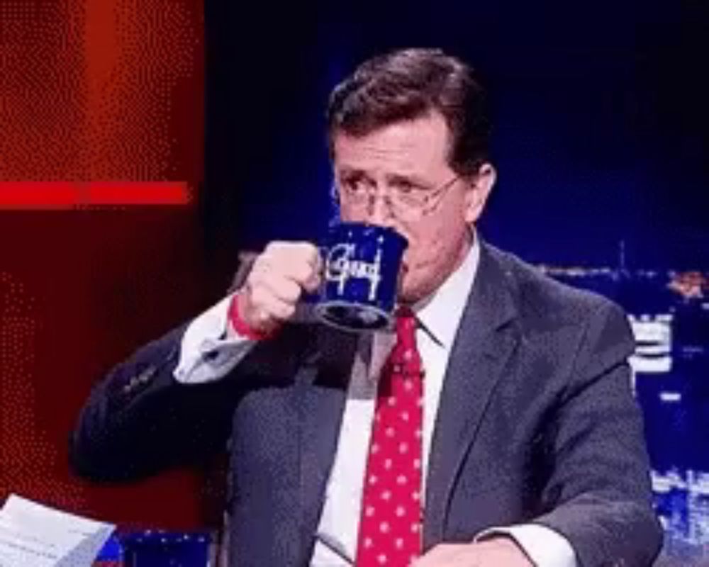 a man in a suit and tie is drinking from a blue mug that says good on it