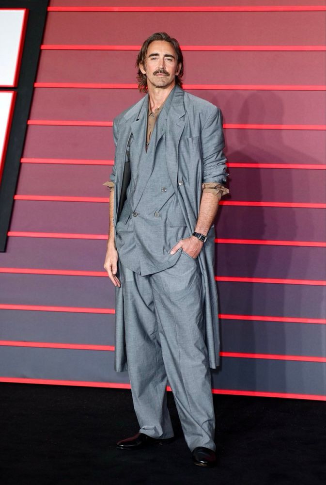 Lee Pace absolutely stylin in a very loose-fitting grey suit and jacket, with a soft brown undershirt. Relaxed stance with the sleeves scrunched and rolled up.