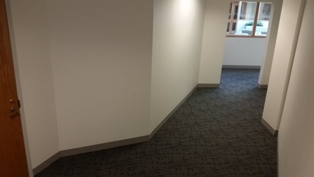 Imagine a normal office building hallway. Cream walls. Grey low-pile carpet. Now imagine this hallway has about twelve different wall segments, all at different angles to one another, almost none of them parallel, like some kind of corporate funhouse.