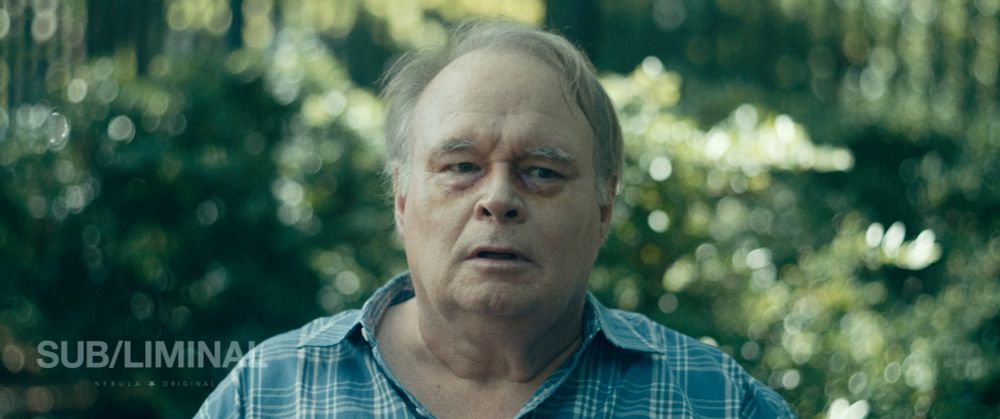 Tom McGowan looks to camera right looking mildly disheveled. 