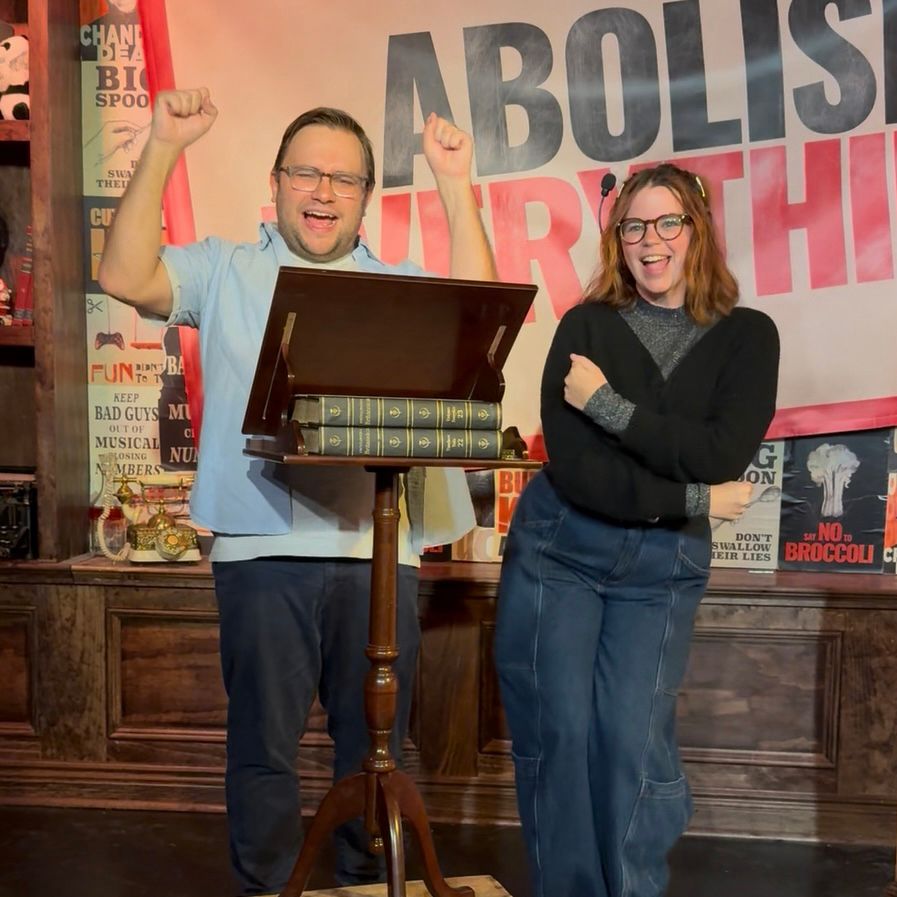 Chandler Dean and Amy Muller stand on the Abolish Everything! set cheering.