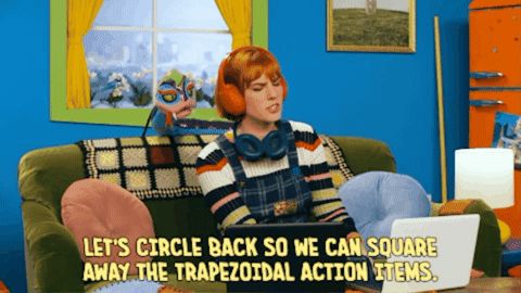 Amy sits on her coach next to Quak the Snake wearing two headphones, a red pair on her head and a blue pair around her neck, with the text underneath that reads, "Let's circle back so we can square away the trapezoidal action items."