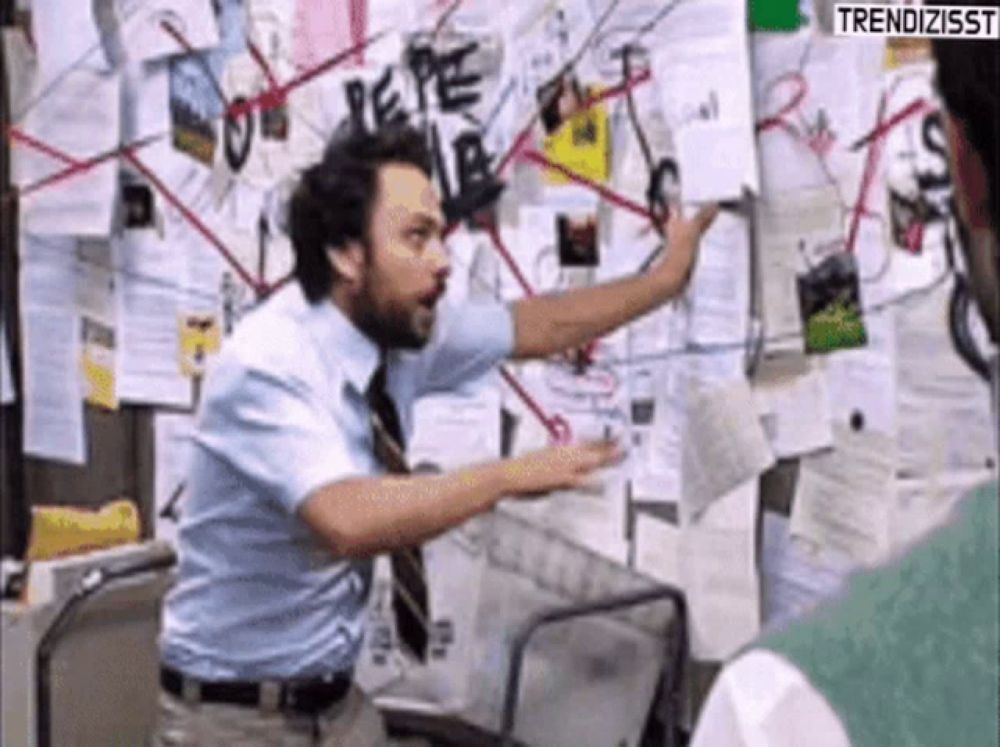 a man in a blue shirt and tie is pointing at a board with papers on it .