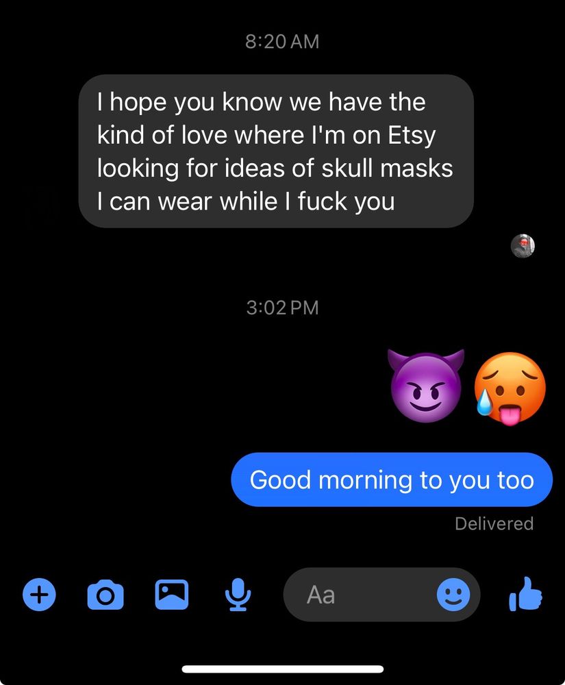 Text exchange screenshot from messenger. Text on left in gray says “I hope you know we have the kind of love where I’m on Etsy looking for ideas of skull masks I can wear while I fuck you.” Text on right is the purple smiling devil emoji and the hot emoji followed by “Good morning to you too”.