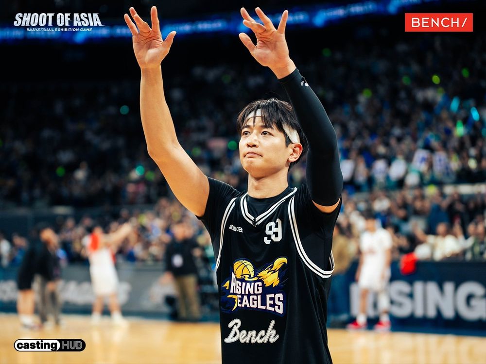 Minho from SHINee raises his arms in celebration on the basketball court.