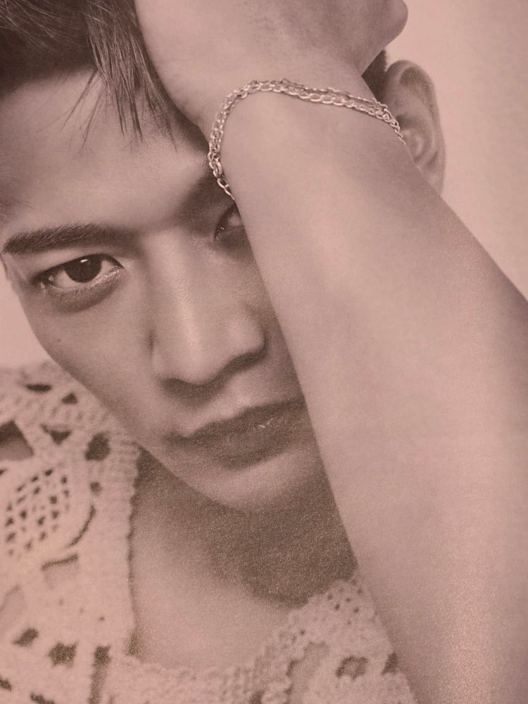 Minho from SHINee in a black and white image, wearing a bracelet on his wrist.
