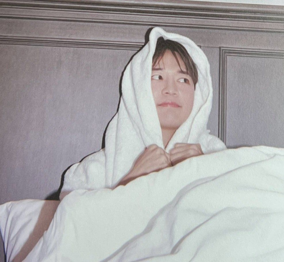Minho from SHINee, wrapped in a towel, exuding a laid-back and comfortable vibe.