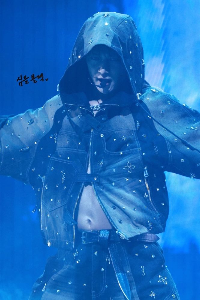 Minho from SHINee in a hoodie and pants, captivating the audience during his solo concert on stage.