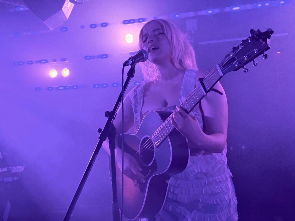 Léa Seb singing and playing the acoustic guitar