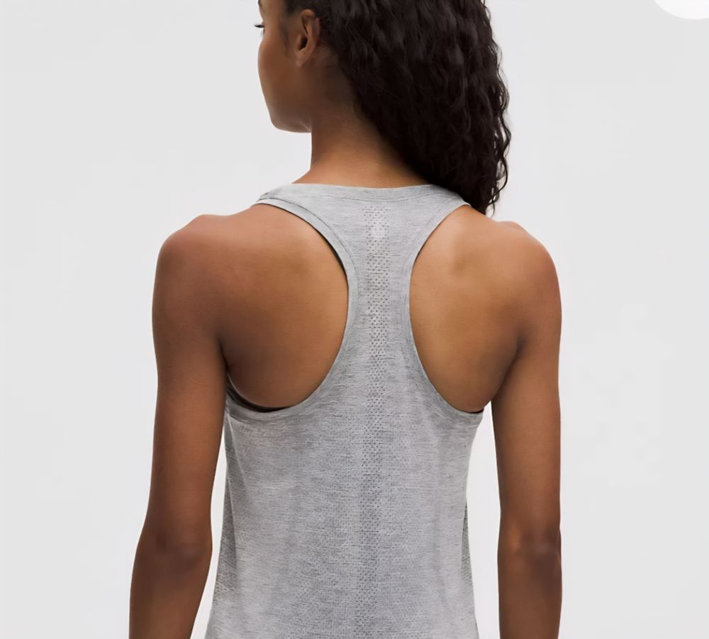 A woman wearing a grey racerback tank top, facing away from the camera.