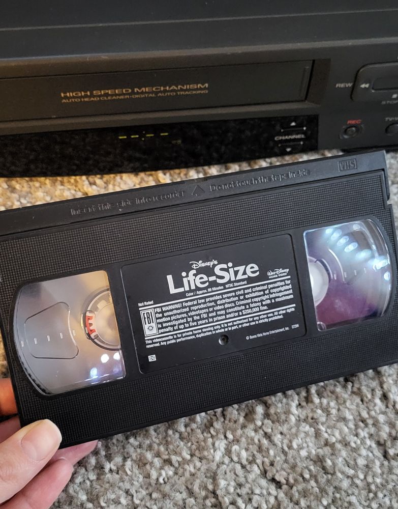 VHS copy of Disney's Life-Size movie held in front of a VCR player.
