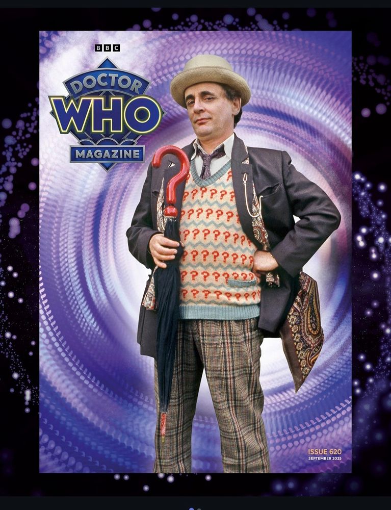 Capa da doctor who magazine com o 7th doutor em sua pose clássica: com a mão na cintura, usando paletó, pulover com os pontos de interrogação, calça xadrez, chapéu e segurando o guarda chuva 