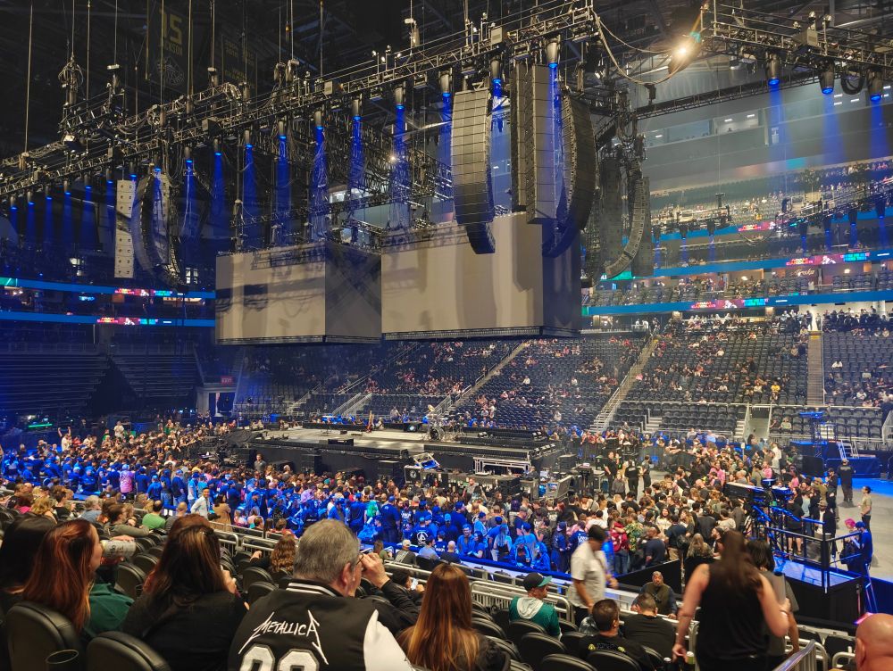 Empty stage in Climate Pledge Arena with a bunch of people milling about