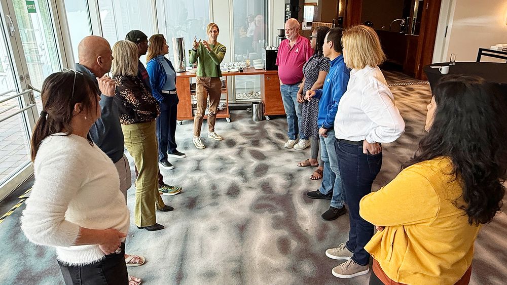 Agile Alliance board meeting 2025 – a photo of multiple people standing in a semi-circle and having a meeting