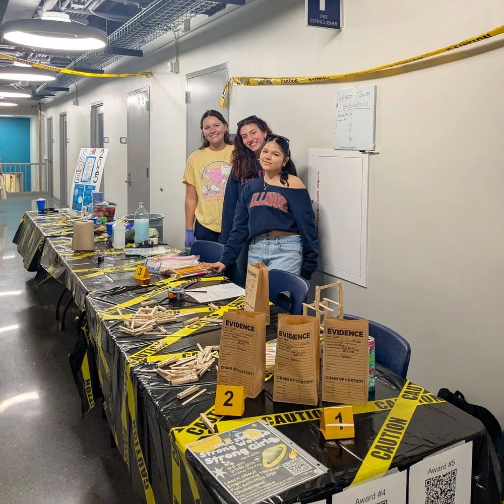 Society of Women Engineers members pose with their booth "SWEne of the Crime".