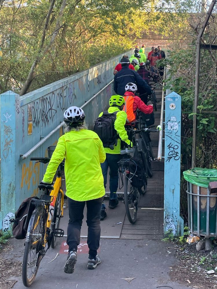 Cyclists walking over narrow bridge