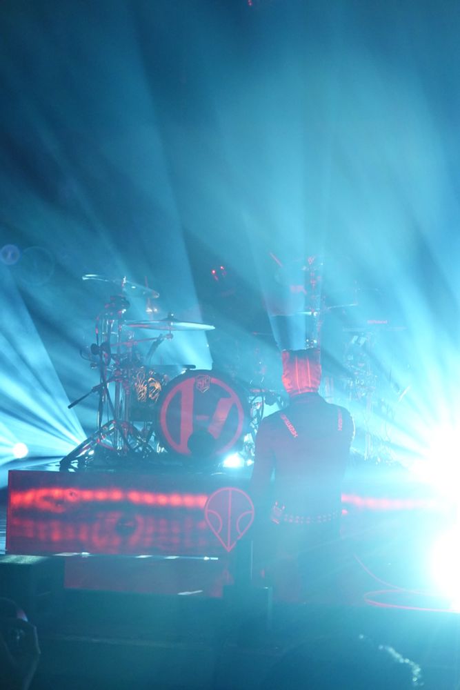 Straight out of camera shot. Tyler is on his knees in front of Josh drum Kit. The lighting is blown out. The only part of Josh you can see is his glowing eyes. 