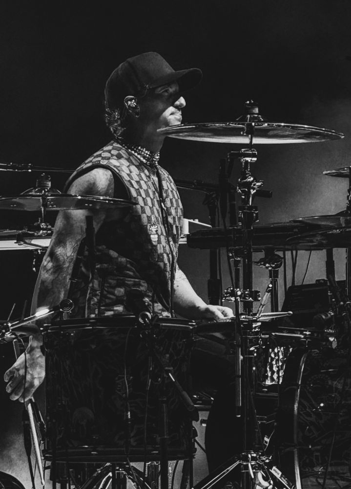 Josh dun sitting at his drums. He’s looking out at the crowd and has a small smile on his face. 