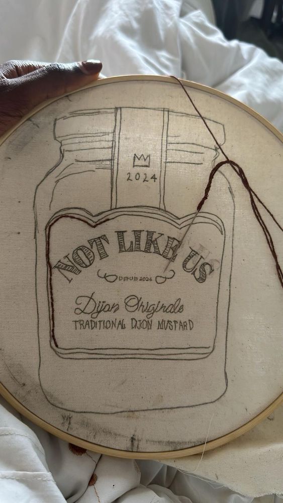 Embroidery loop with outline of a pot of mustard drawn on canvas