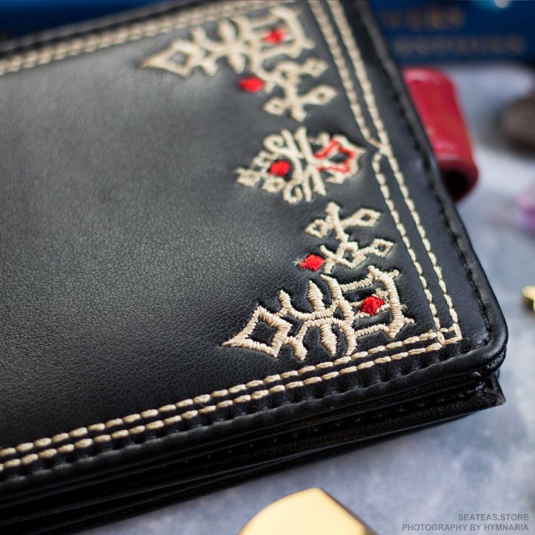 Black bifold wallet with G'raha Tia's shirt pattern embroidered on the front.