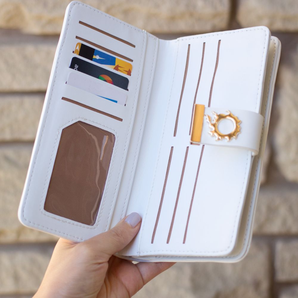 A white clutch style wallet with the meteor symbol from FF14. It is being held open by the model to show a window slot for your ID and several more card slots and a money slot.