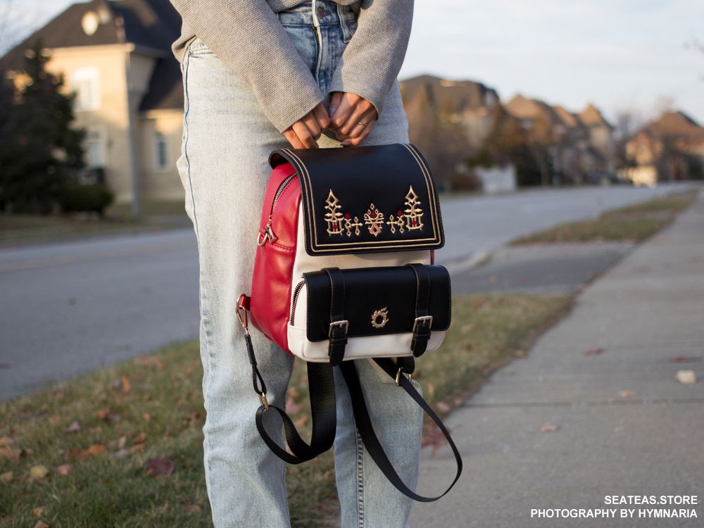 A backpack that can be transformed into a bag. It has G'raha Tia's shirt design embroidered on the front with gold hardware of the Meteor icon. 