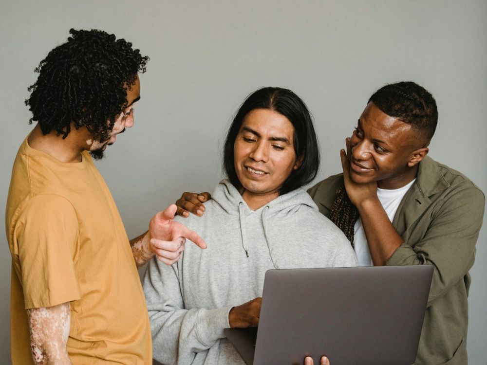 Three men stood around a laptop attending an online group discussion about what boys and men know about their reproductive health. 