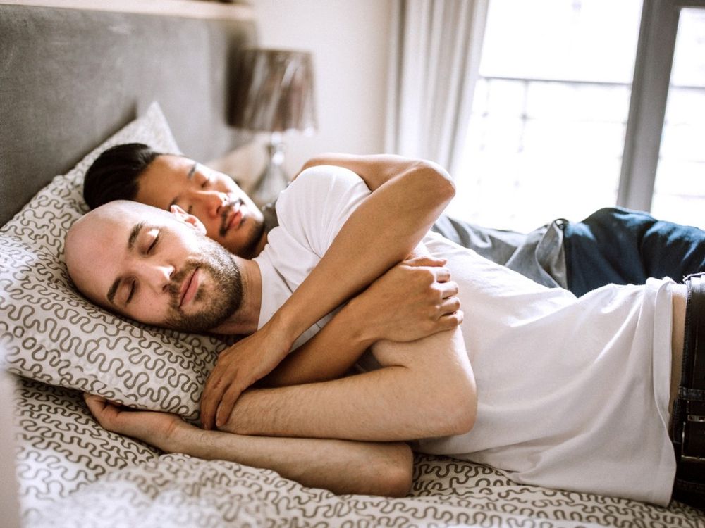 Two men lying on a bed together