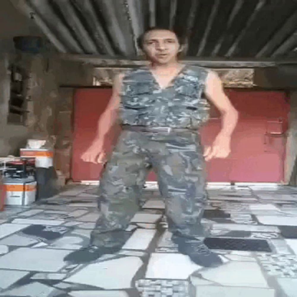 a man in a camo vest and pants is standing on a tiled floor