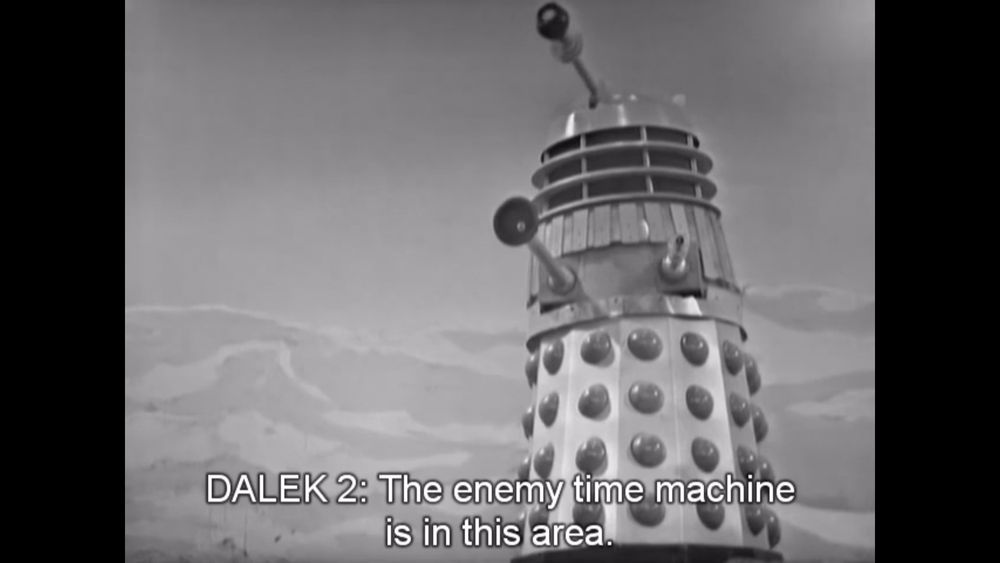 screenshot from Doctor Who s02e08 The Chase ep2, dalek stands on sand and says "The enemy time machine is in this area"