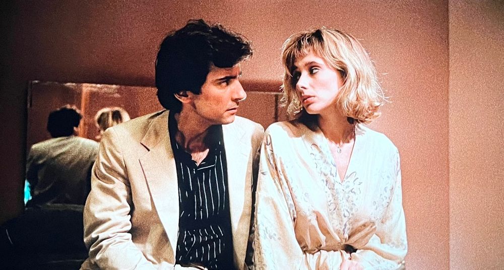 Rosanna Arquette and Griffin Dunne sitting and reflecting in the mirror behind.