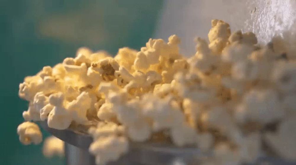 a pile of popcorn is being poured into a bowl