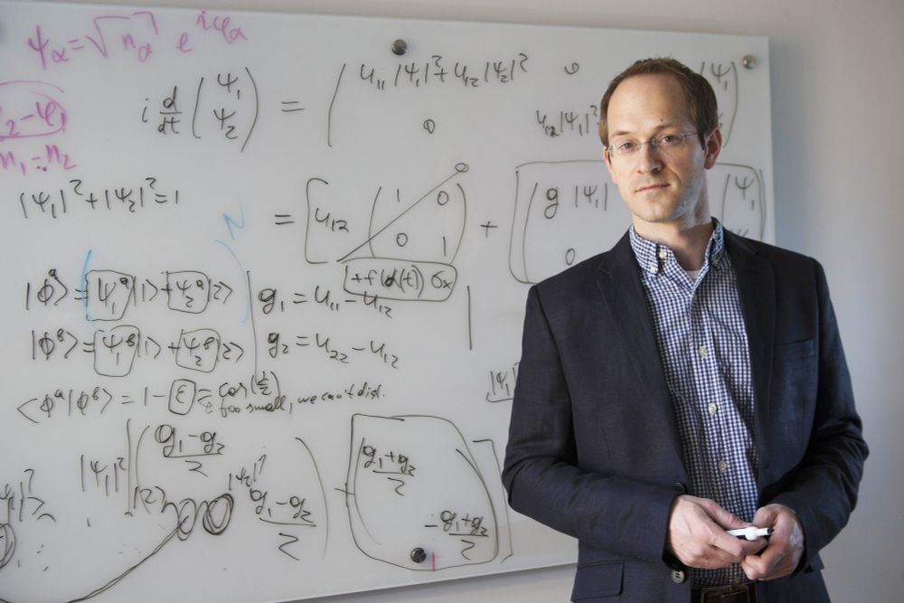 Andrew Childs standing in front of a whiteboard marked with equations