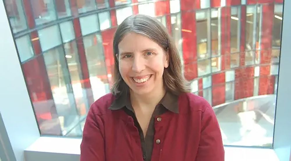 Gretchen Campbell headshot in front of a Physical Sciences Complex window