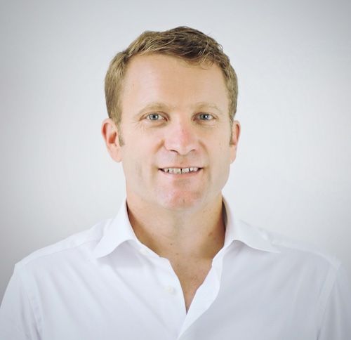 Adam Wenchel wearing a white shirt and smiling at the camera