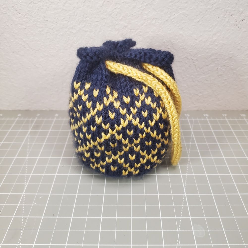 Small knitted drawstring bag in blue with yellow colorwork.