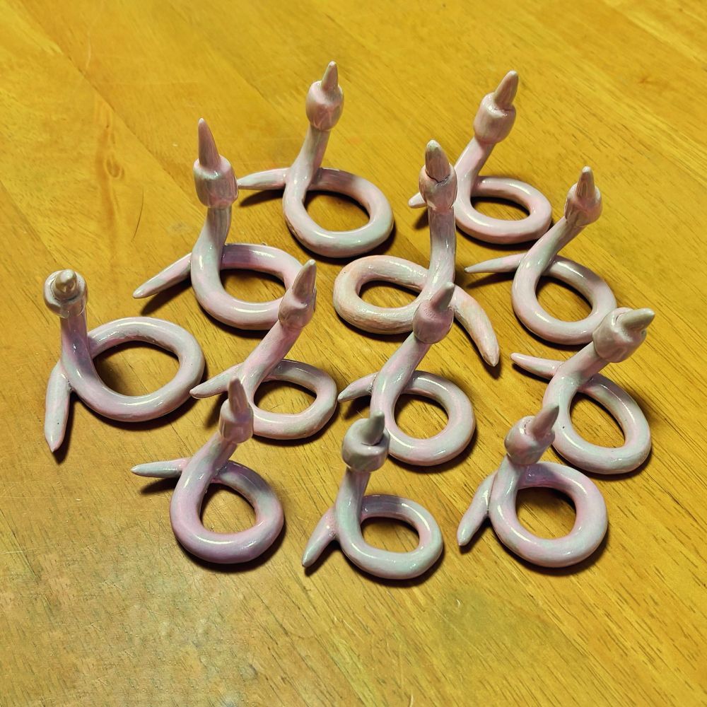 A small army of 12 large ceramic worms on a wooden table 
