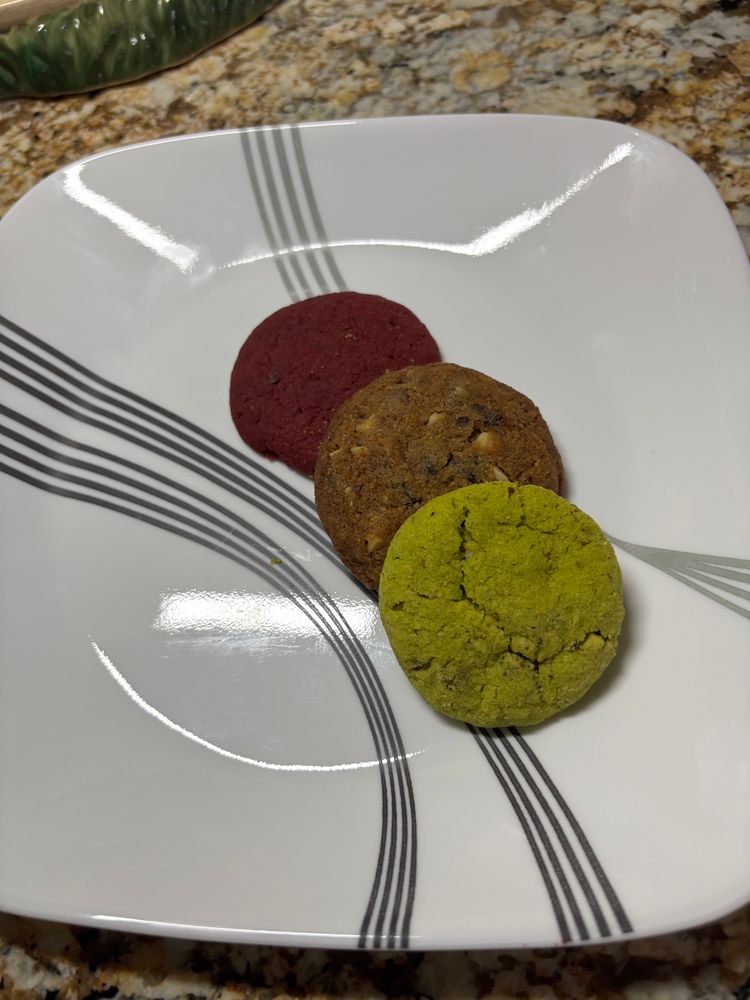 27 baked these! Three cookies on a plate, one is pistachio, the second is a brown sugar cookie with fig and white chocolate, the third is a sugar cookie base with black cherry.