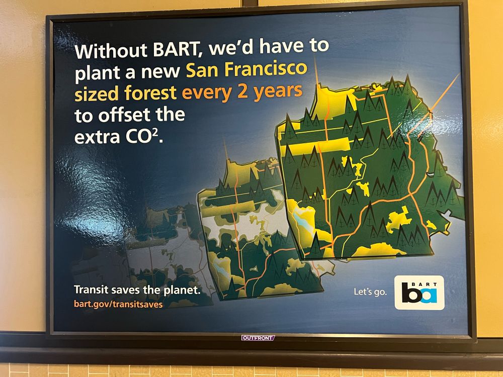 A sign that reads, “Without BART, we'd have to plant a new San Francisco sized forest every 2 years to offset the extra CO2”, but the 2 in CO2 is up high instead of down low.