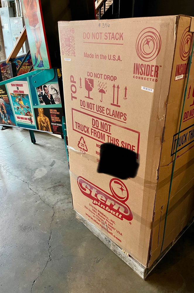 A large box holding a new pinball machine from Stern. There’s a James Bond pinball machine in the background.