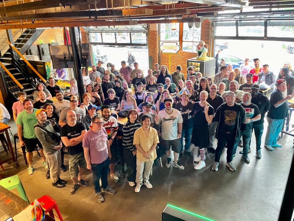 A group of people waiting to play a pinball tournament.